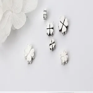 Detailed macro view of silver four-leaf flower spacer beads for DIY handmade jewelry
