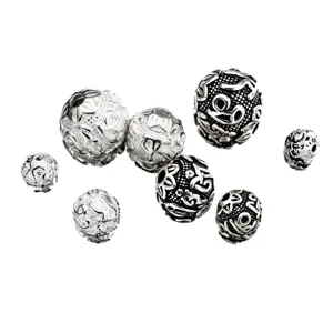 Detailed close-up of vintage Thai silver spacer beads with engraved mantra patterns