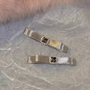Detail view of champagne satin duckbill hair clips with square crystal and rhinestones