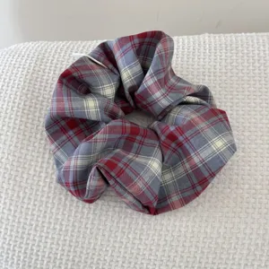 Detailed macro shot of a vintage red and blue plaid oversized fabric hair scrunchie