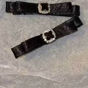 Macro view showing the elegant black satin fabric and rhinestone buckle of the hair clips