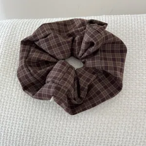 Detailed view of a retro brown plaid scrunchie hair tie showing fabric texture
