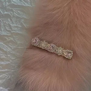 Elegant pink satin hair clip with square rhinestones shown on a soft pink fur background.