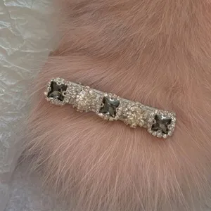 Close-up detail of sparkling rhinestone hair clip on soft pink faux fur background