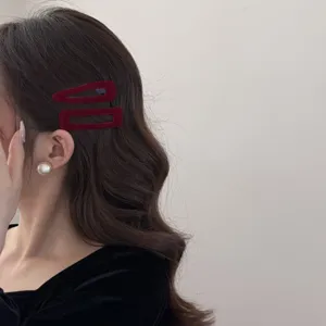 Détail de barrettes géométriques en velours bordeaux et boucle d'oreille sur modèle