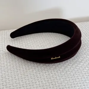 Primo piano di un cerchietto imbottito in velluto retrò con elegante scritta dorata handmade.