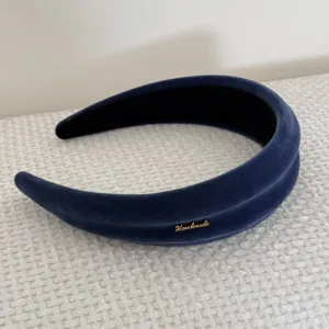Dettaglio di una fascia retrò in velluto blu con una targhetta dorata fatta a mano.