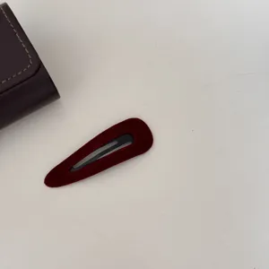 Gros plan d'une pince à cheveux vintage en velours rouge foncé en forme de goutte.
