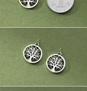 Detailed view of hollow S925 sterling silver tree of life pendants on green texture