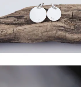 Close-up detail of two polished 925 sterling silver round charm pendants for DIY jewelry
