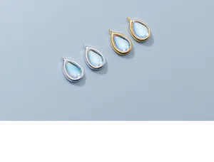 Close-up of teardrop pendants with synthetic moonstone in silver and gold plated frames