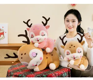 Morbidi peluche di renna in rosa e marrone tenuti da una modella donna sorridente