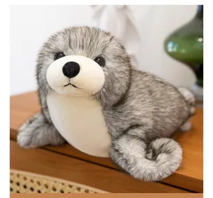 Vista detallada de un peluche de foca gris realista sobre una superficie de madera