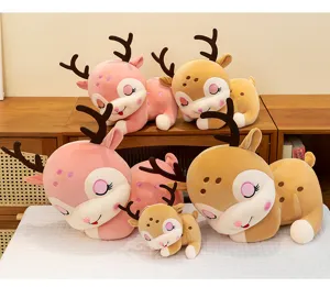 Gruppo di simpatici peluche di renna rosa e marroni disposti su un mobile in legno e un letto.