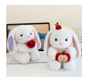 Detailopname van twee schattige witte pluche konijnen met een roos en een appel op bureau