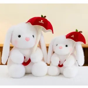 Detail van twee witte pluche konijnen met rode appelvormige paraplu's.