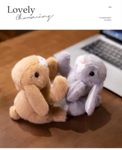 Paar entzückende langohrige Plüschhasen auf einem Holzschreibtisch neben einem Laptop