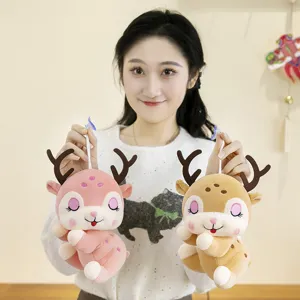 Due simpatici peluche a forma di renna in rosa e marrone tenuti da una modella per arredo