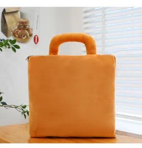 Close-up of a soft orange plush bag-style pillow featuring a handle and zipper detail