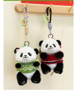 Dos lindos llaveros de panda de peluche con suéteres de colores colgados en ganchos