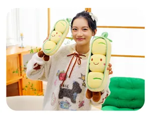 Ein asiatisches Model hält zwei süße grüne Erbsenschoten-Plüschtiere mit lachenden Gesichtern