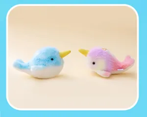 Close-up of two cute plush narwhal bag charms in pastel blue and rainbow colors for kids.