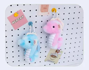 Adorable plush seahorse keychains in pink and blue colors hanging on a decorative white pegboard