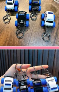 Detailed view of four alloy police car keychains with large blue wheels held by hand.