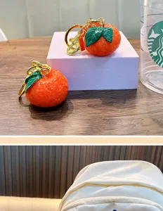 Realistic resin mandarin orange keychain detail showing vibrant skin texture and leaves.