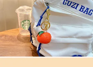 Detailed view of a realistic resin sugar orange keychain charm attached to a white backpack zipper