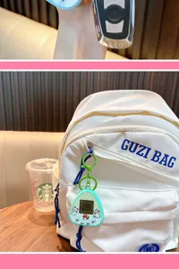 Gros plan d'un porte-clés de jeu d'animaux virtuels vert accroché à un sac à dos blanc.
