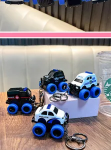 Close-up of alloy police car keychains with large blue wheels on a wooden surface.