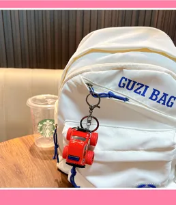 Detailed macro view of a red fire truck toy keychain accessory on a white backpack