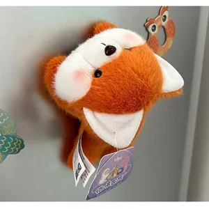 Detailed macro view of a cute orange fox plush magnet attached to a gray refrigerator surface
