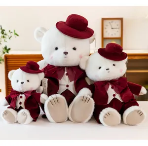 Three plush teddy bears wearing elegant wine-red wedding outfits and matching hats.