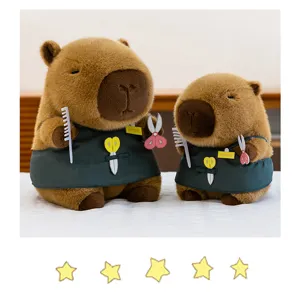 Detalle de dos adorables peluches de carpincho con temática de peluquero y delantales verdes.