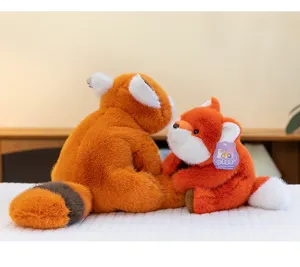 Primer plano de un lindo peluche de zorro naranja en una acogedora cama blanca