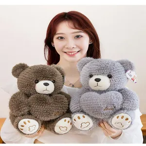 Soft sitting plush teddy bears in brown and grey with embroidered hearts held by a model