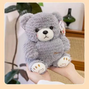Detail view of a soft gray plush teddy bear with embroidered heart and paw details.
