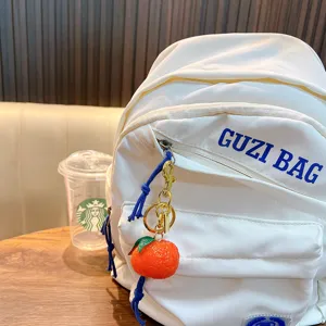 Realistic resin tangerine keychain attached to a white backpack as a cute bag charm