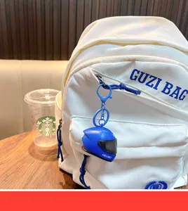 Detailed view of a blue motorcycle helmet keychain attached to a white backpack.