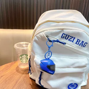 Glowing blue motorcycle helmet keychain light pendant on a stylish white backpack