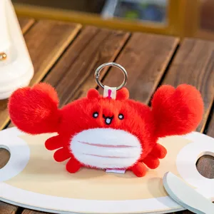 Macro view of a cute red plush crab keychain with detailed embroidered facial features.