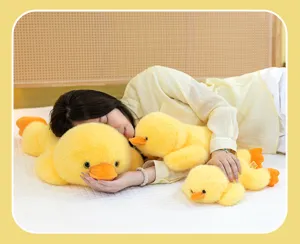 Detail shot of cute yellow duck plush toy sleeping pillows held by a model on a bed