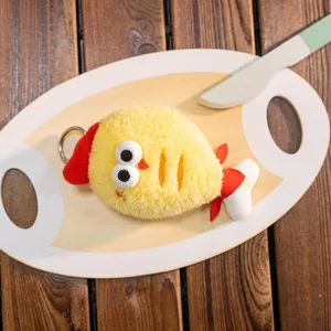 Adorable cute yellow plush chicken keychain charm displayed on a wooden serving board prop.