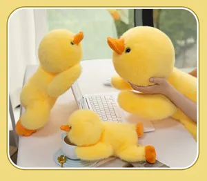 Detailed shot of cute yellow duck plush toys on a desk with a white laptop