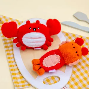 Close-up of cute plush crab and lobster keychain pendants on a wooden board