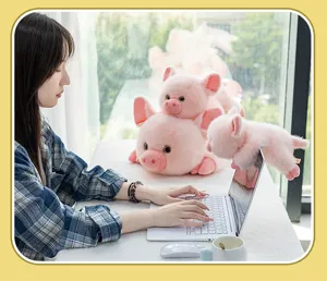 Simpatici peluche a forma di maialino rosa su una scrivania bianca accanto a un laptop.