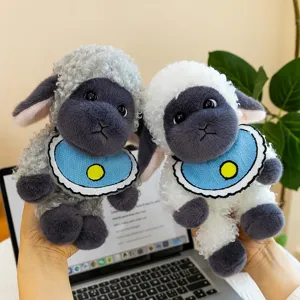 Cute black-faced sheep plush toys with curly fur and blue bibs on desk