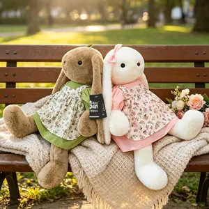 Twee schattige pluche konijnenpoppen in bloemenjurken op een bankje